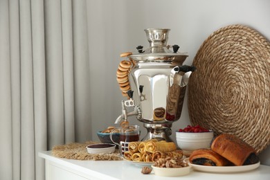 Traditional Russian samovar with treats on white table at home. Space for text