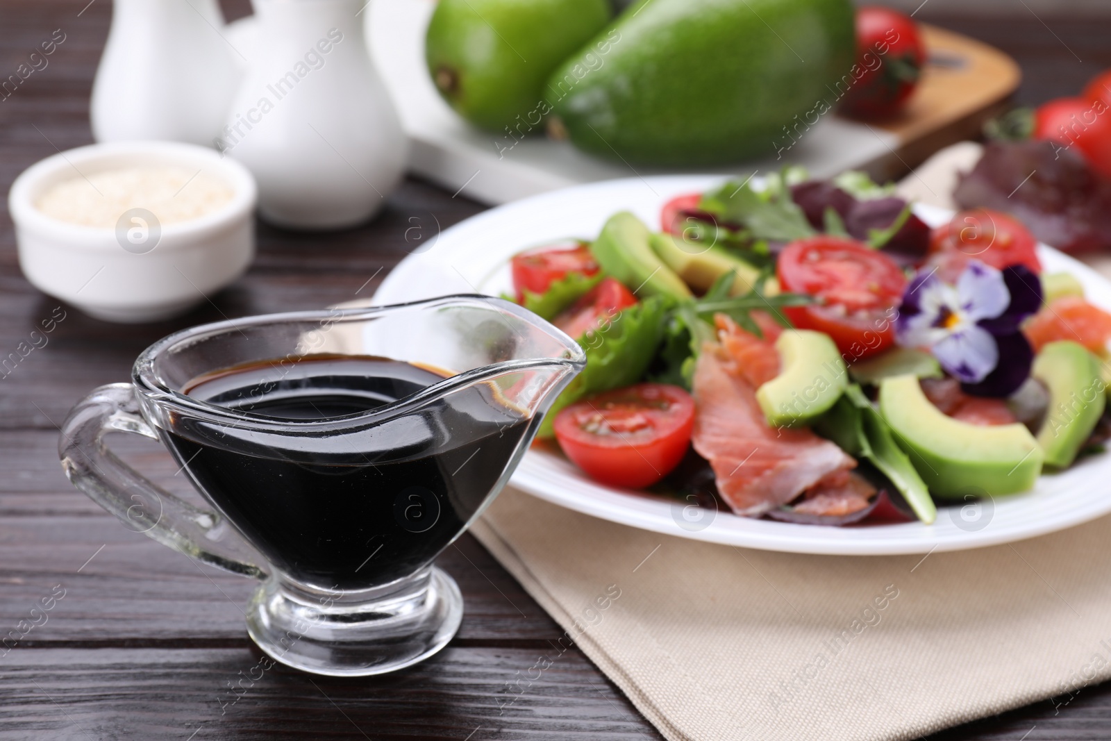 Photo of Tasty soy sauce and plate with salad on wooden table, selective focus