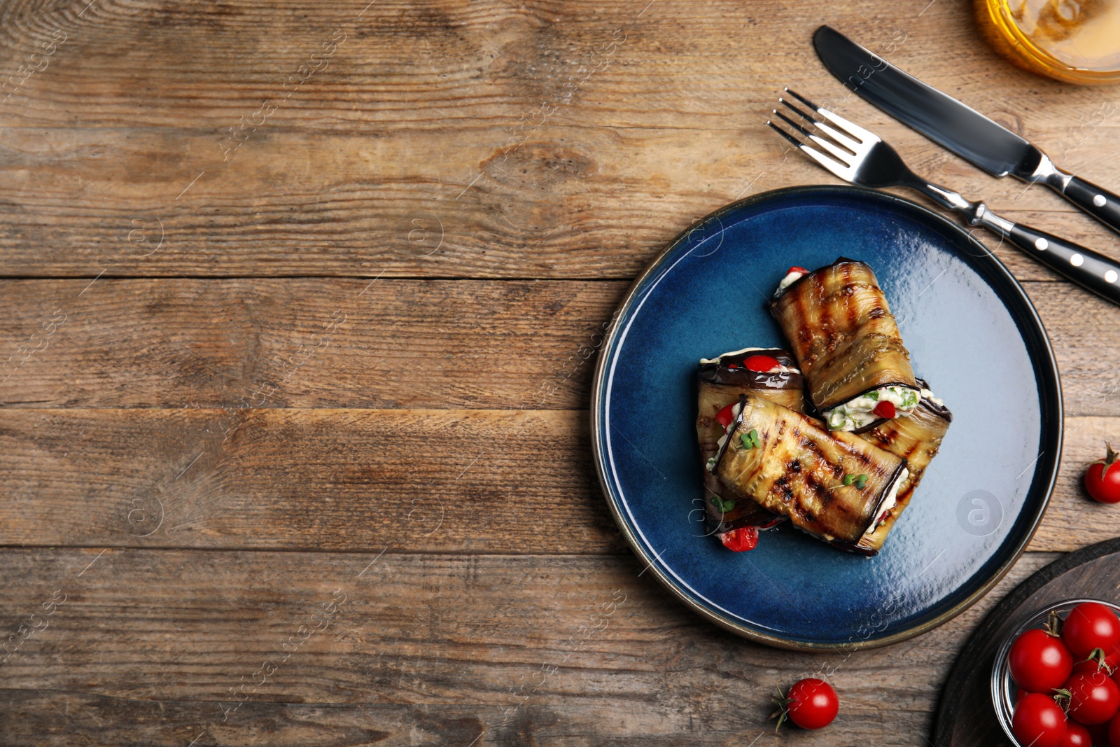 Photo of Delicious baked eggplant rolls served on wooden table, flat lay. Space for text