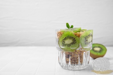 Delicious dessert with kiwi and muesli on white table. Space for text