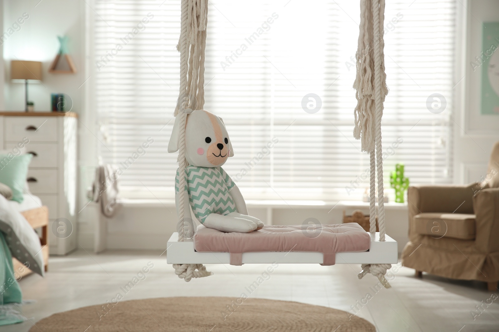 Photo of Stylish swing with toy in child's room. Interior design