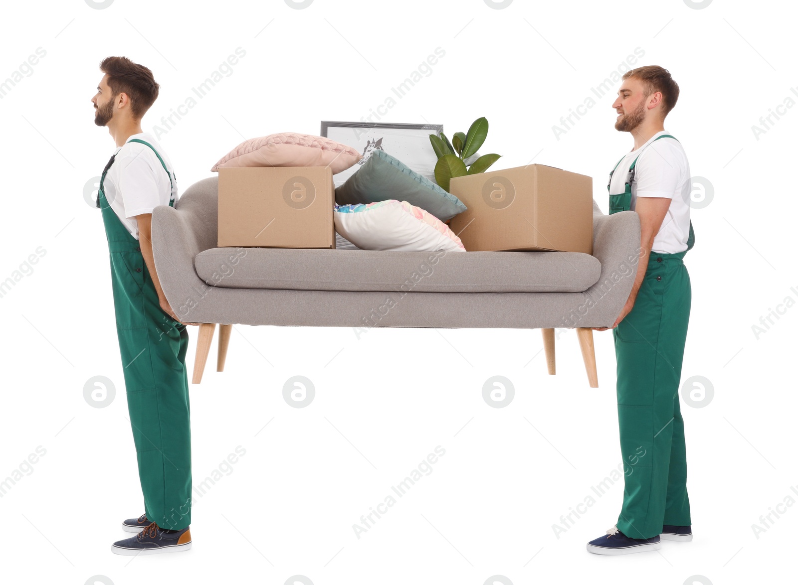 Photo of Young workers carrying sofa with stuff isolated on white. Moving service