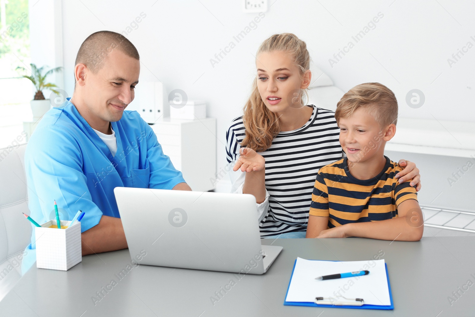 Photo of Male medical assistant explaining physical examination result to mother and child in clinic