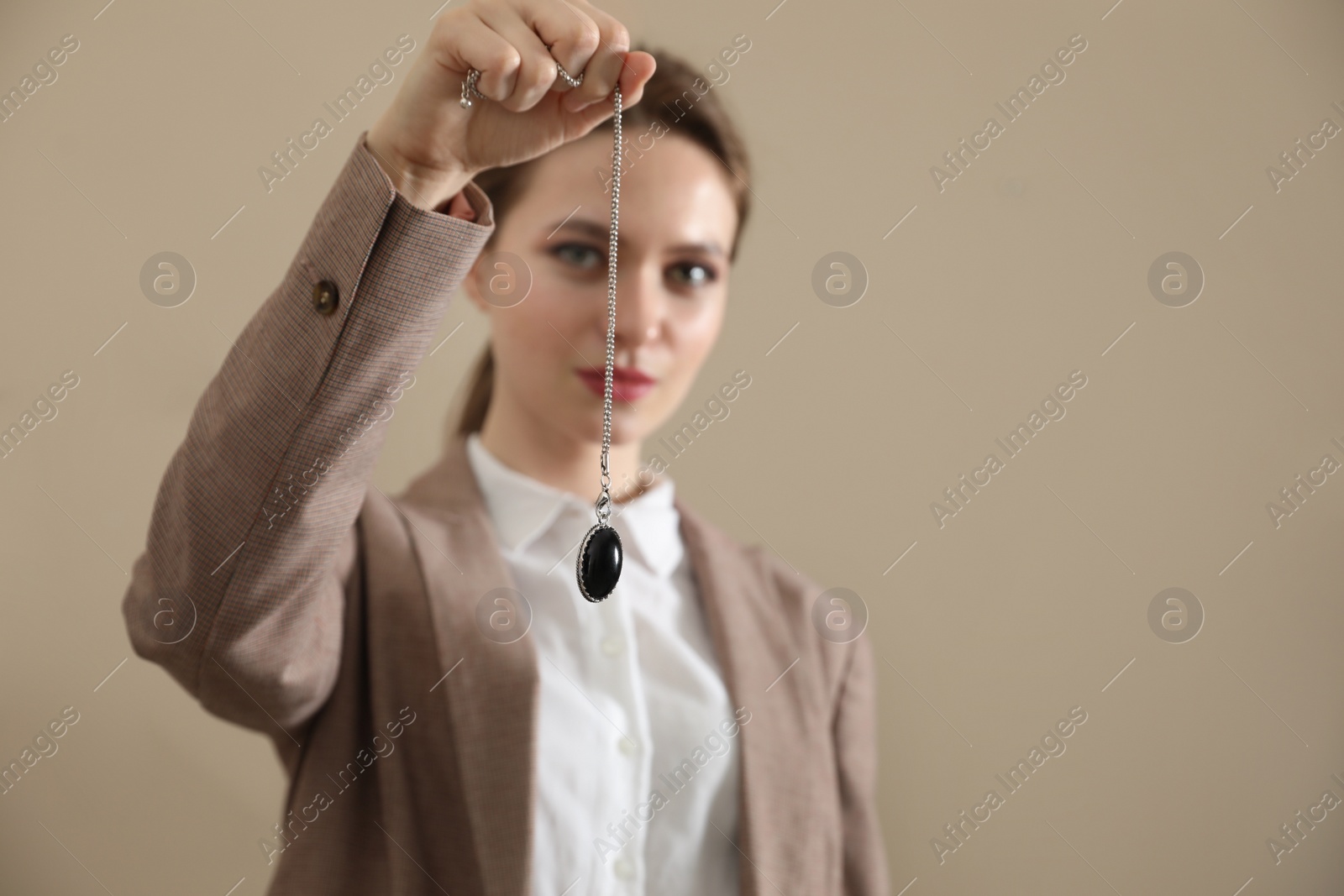 Photo of Psychotherapist with pendulum on beige background, space for text. Hypnotherapy session