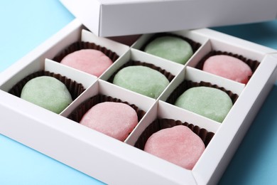 Photo of Many different delicious mochi in box on light blue background, closeup. Traditional Japanese dessert