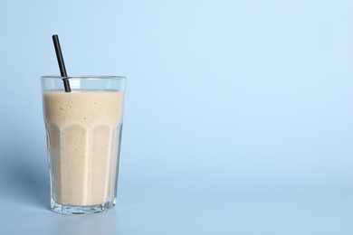 Photo of Glass of tasty smoothie with straw on light blue background. Space for text