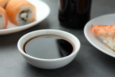 Photo of Bowl of tasty soy sauce on grey table, closeup