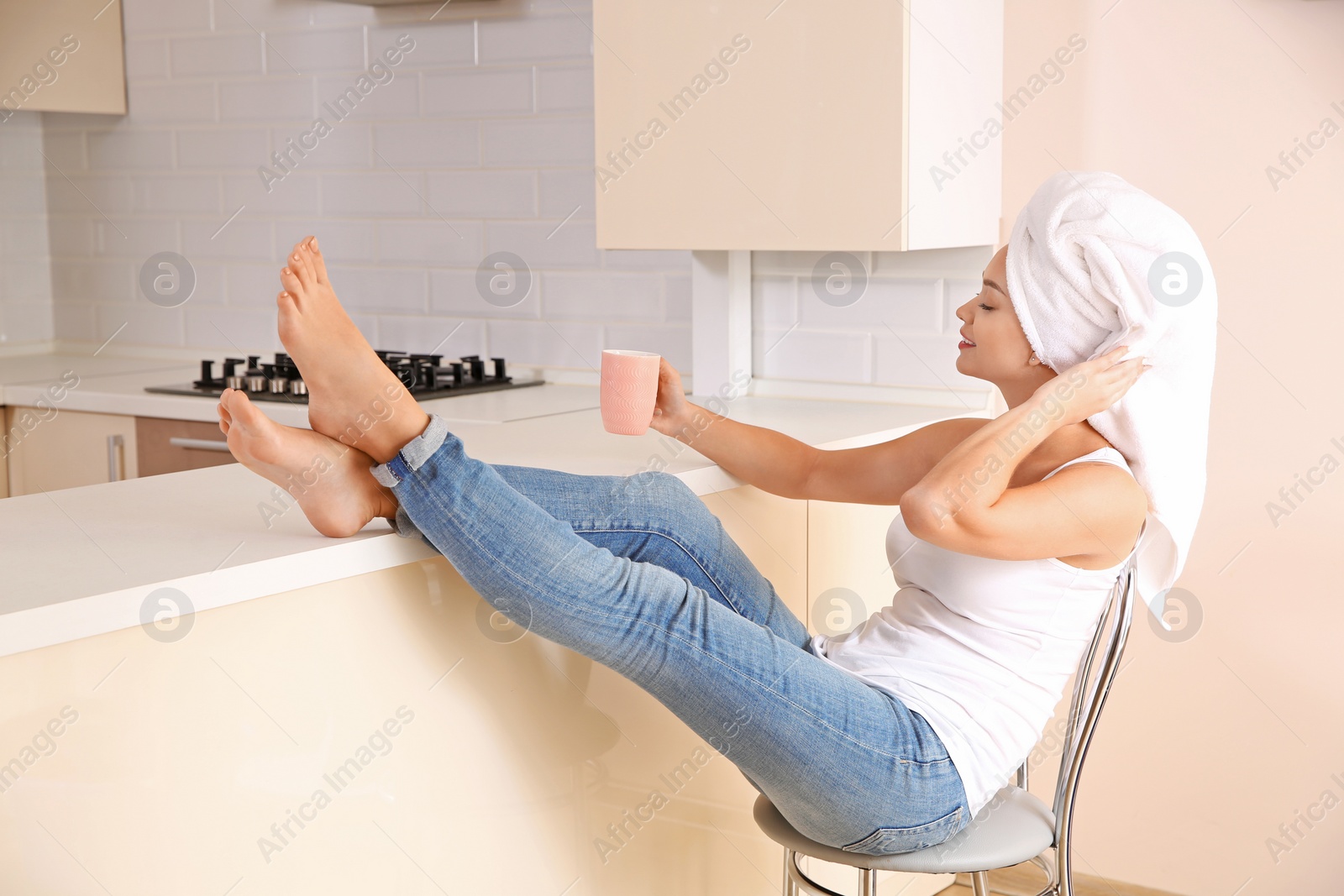 Photo of Beautiful woman with hair wrapped in towel sitting on chair at home