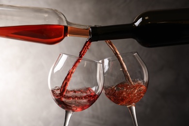 Pouring different wines from bottles into glasses on dark background