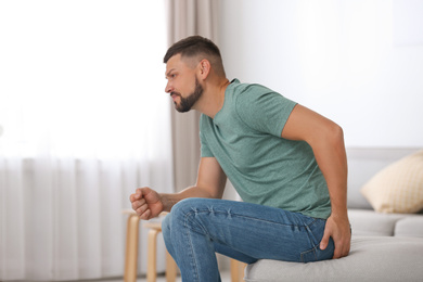 Photo of Man suffering from hemorrhoid in living room