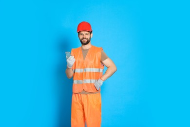 Man in reflective uniform with smartphone on light blue background