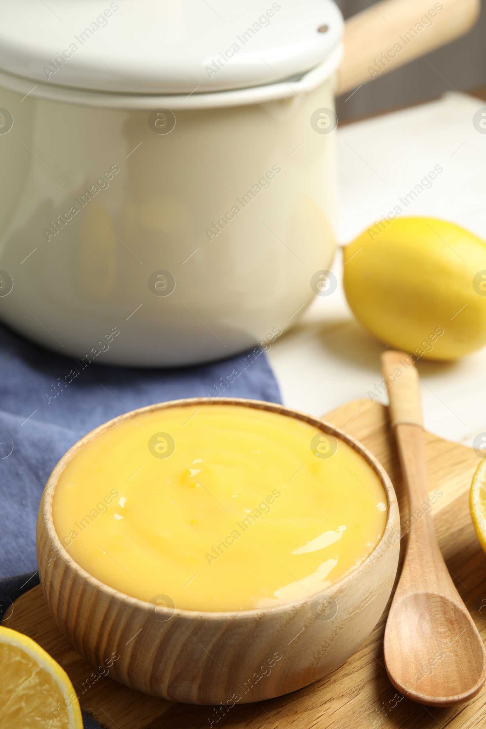 Photo of Delicious lemon curd in bowl on wooden board