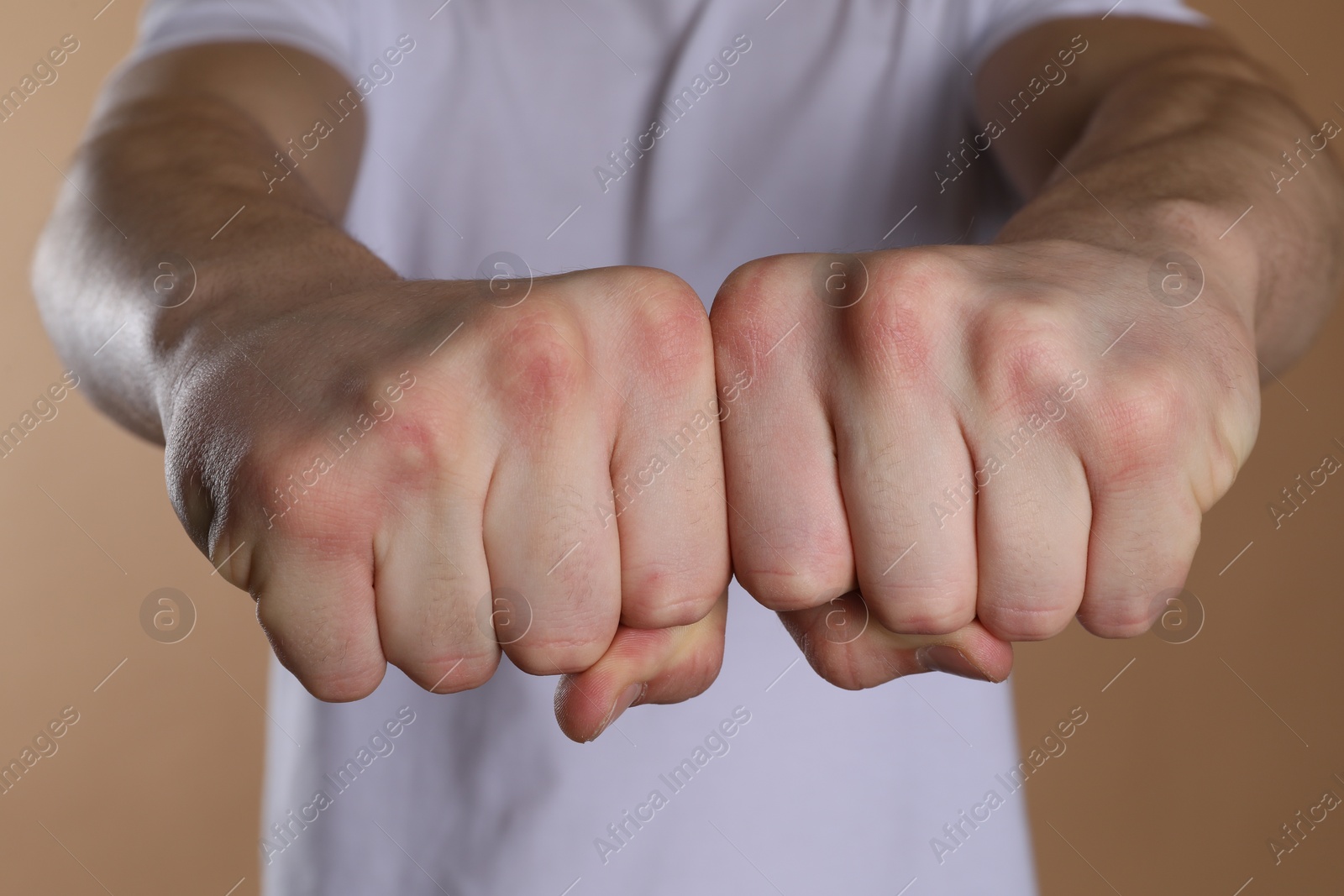 Photo of Man showing fists with space for tattoo on beige background, selective focus