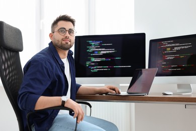 Photo of Young programmer working at desk in office