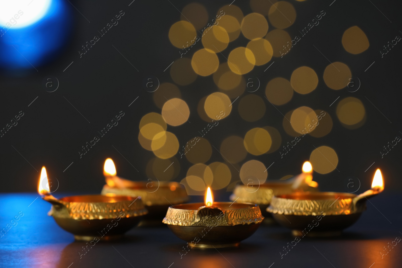 Photo of Lit diya lamps on dark table. Diwali celebration