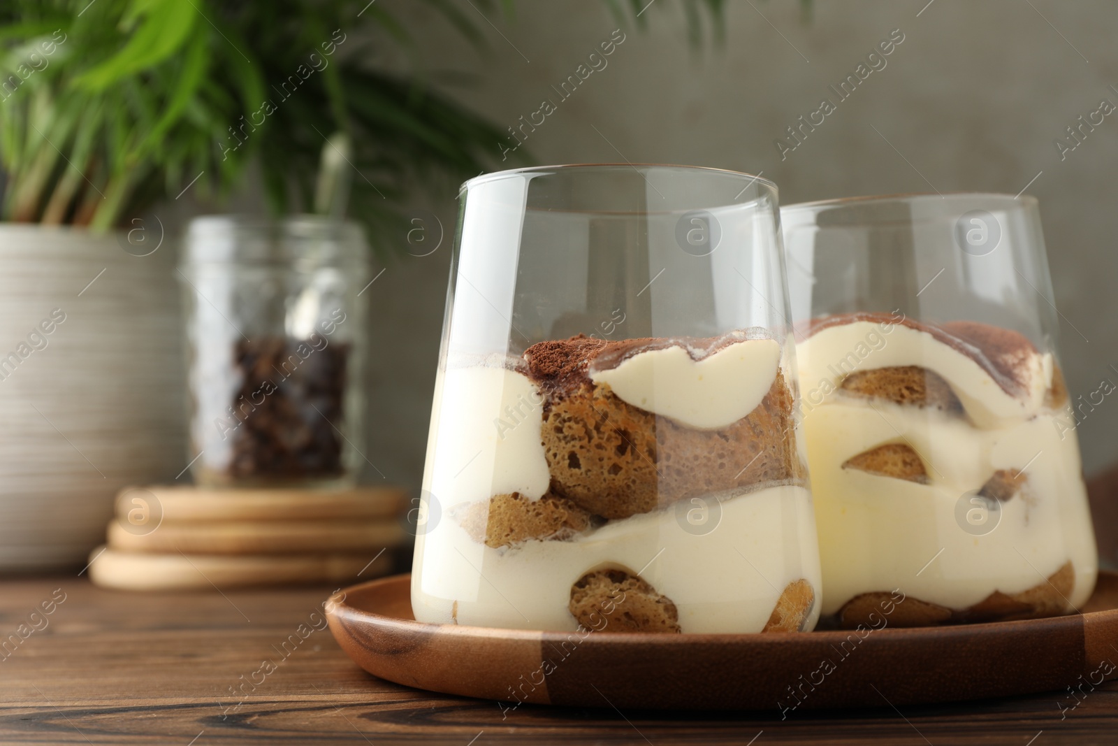 Photo of Delicious tiramisu in glasses on wooden table, closeup