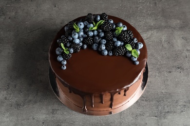 Photo of Fresh delicious homemade chocolate cake with berries on gray table