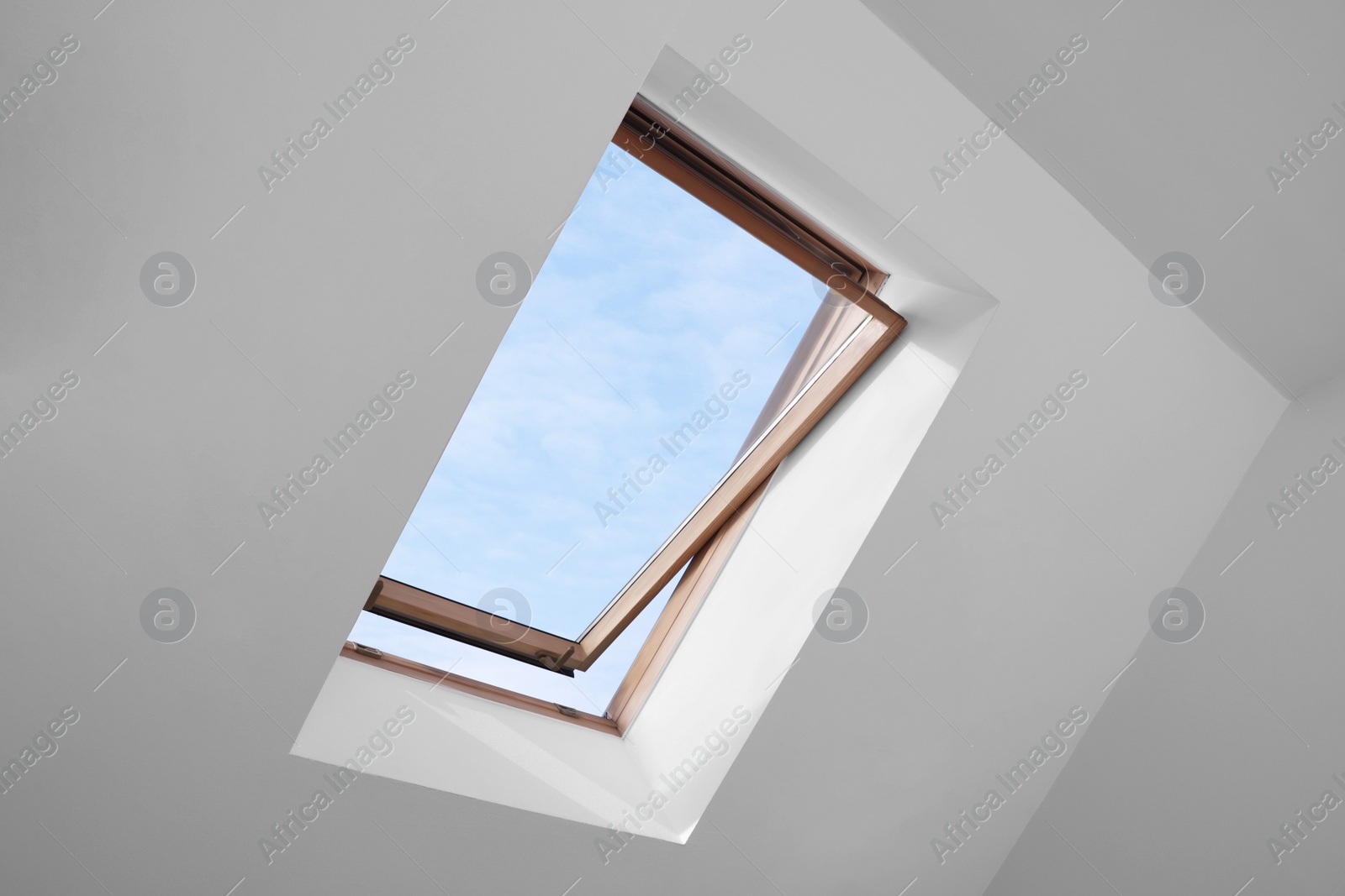 Photo of Open skylight roof window and lamps on slanted ceiling in attic room, low angle view