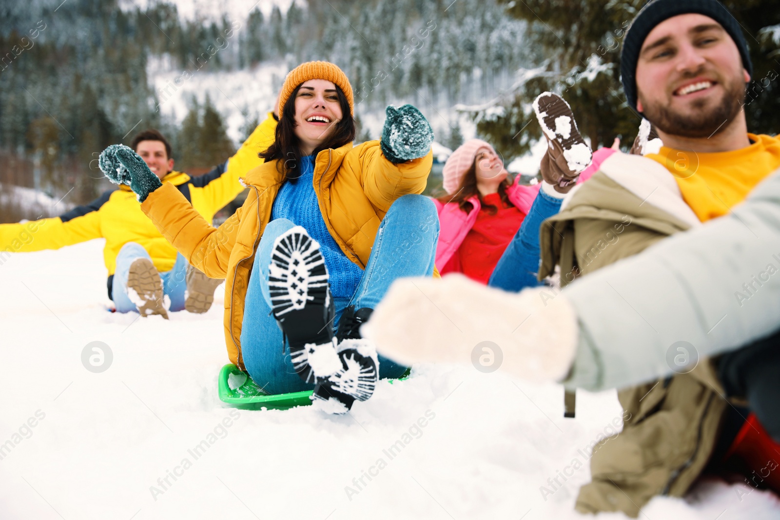 Photo of Group of friends having fun and sledding on snowy day. Winter vacation