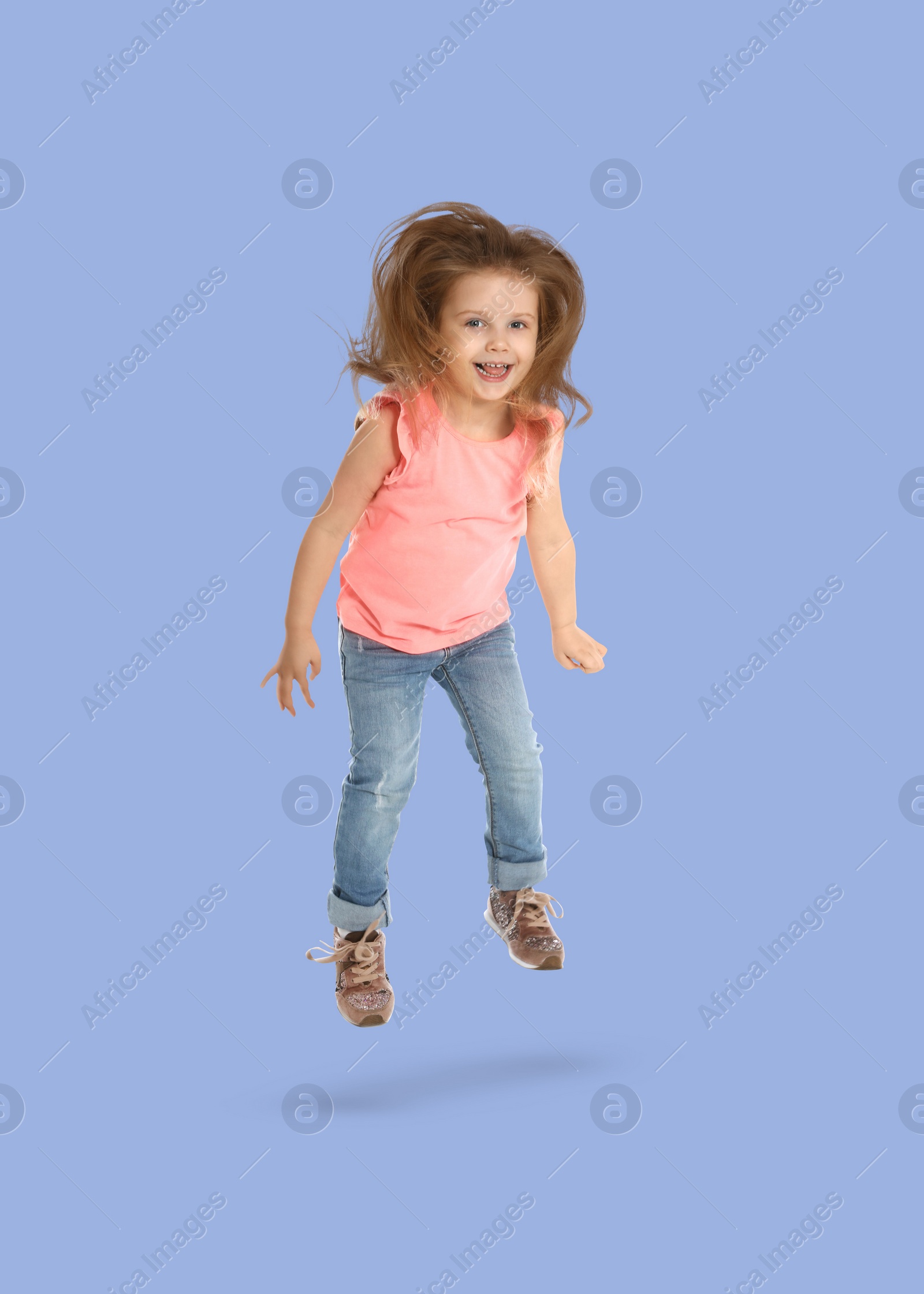 Image of Happy cute girl jumping on light blue background