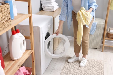 Photo of Woman with sweatshirt near washing machine in laundry room, closeup