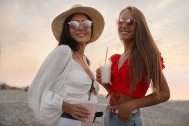 Photo of Beautiful young women with tasty milk shakes on beach