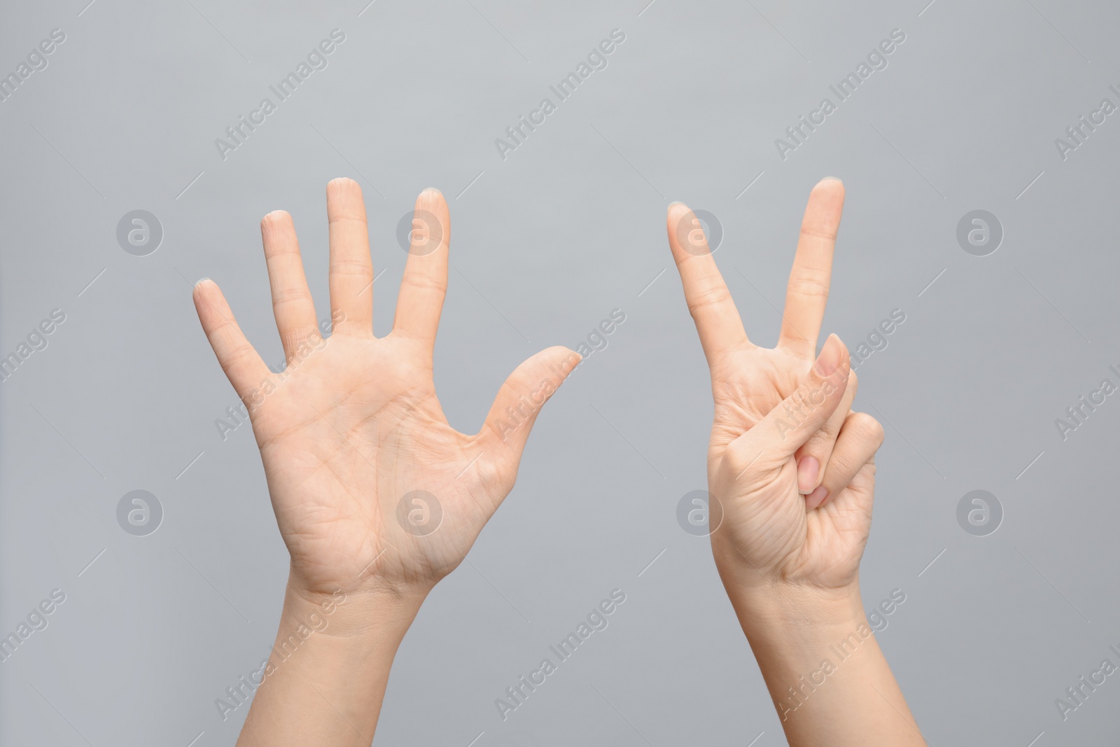 Photo of Woman showing sign seven on grey background, closeup. Body language