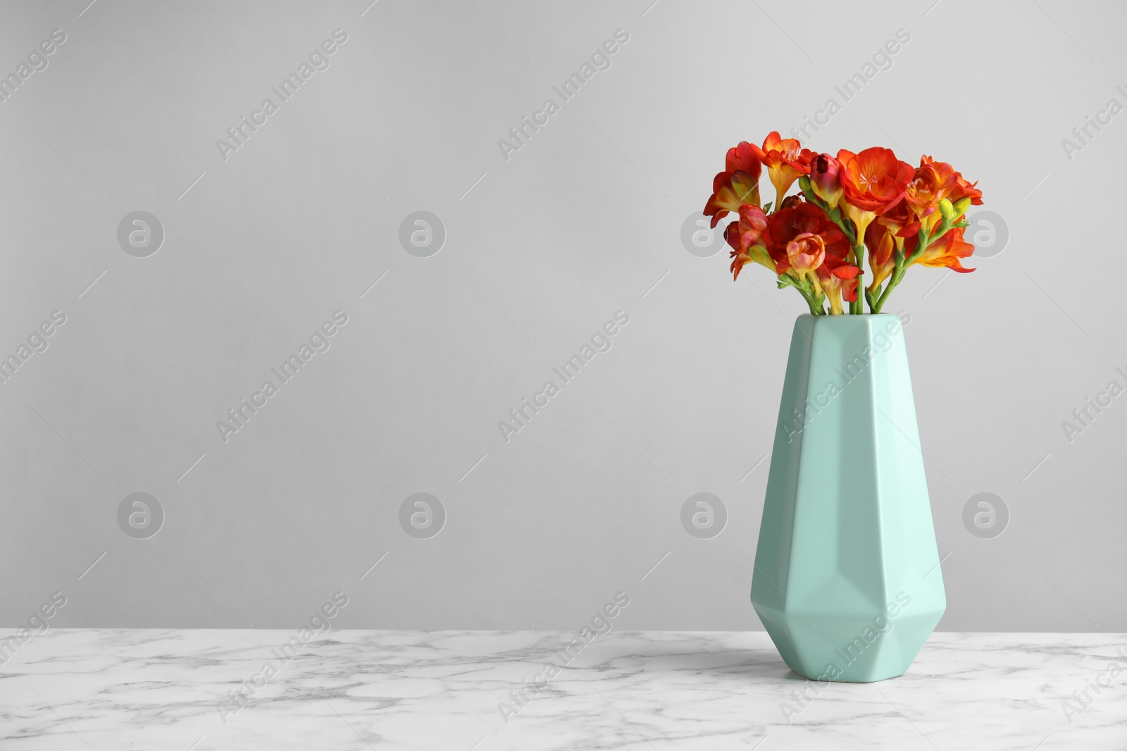 Photo of Bouquet of spring freesia flowers in vase on table. Space for text