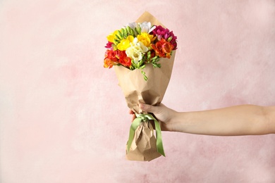 Photo of Woman holding bouquet of beautiful spring freesia flowers on color background