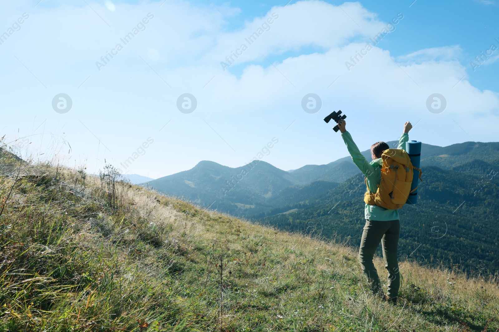 Photo of Happy tourist with hiking equipment and binoculars in mountains, back view