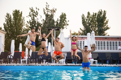Happy young friends jumping in swimming pool