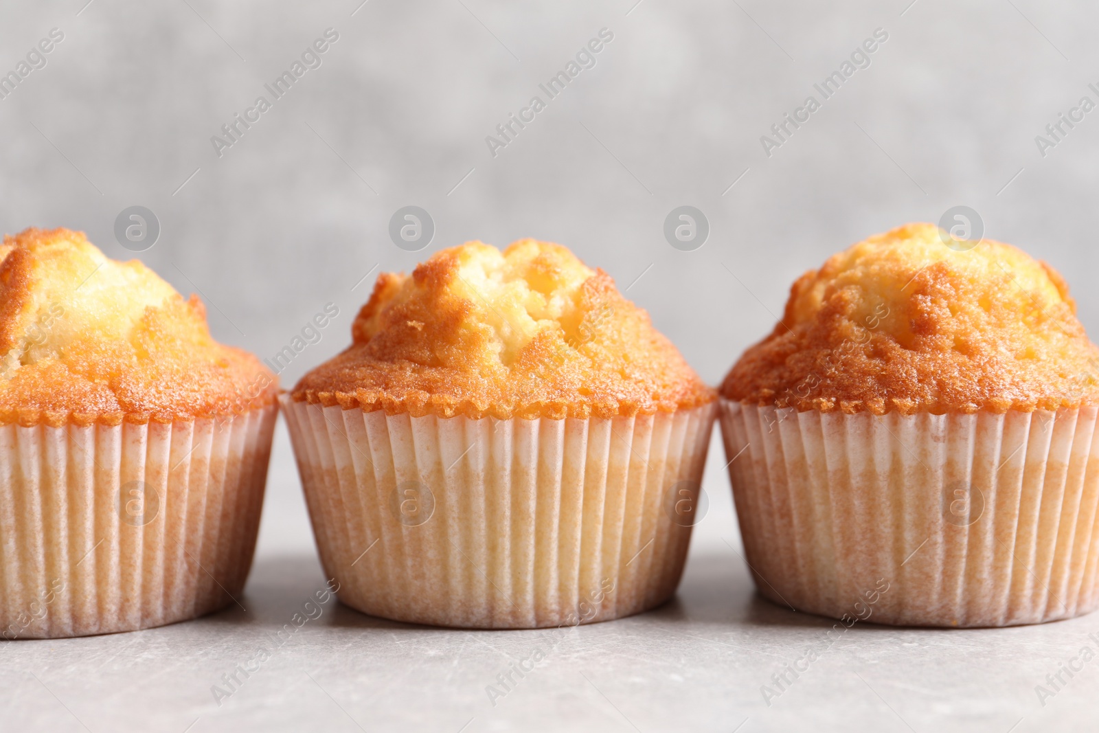 Photo of Tasty muffins on light grey table, closeup. Fresh pastry