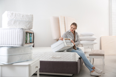 Young woman choosing mattress in furniture store