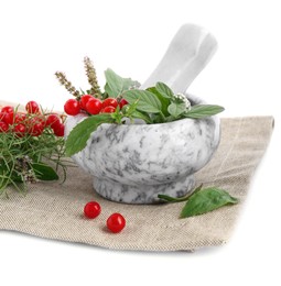Cloth and marble mortar with different herbs, berries and pestle on white background