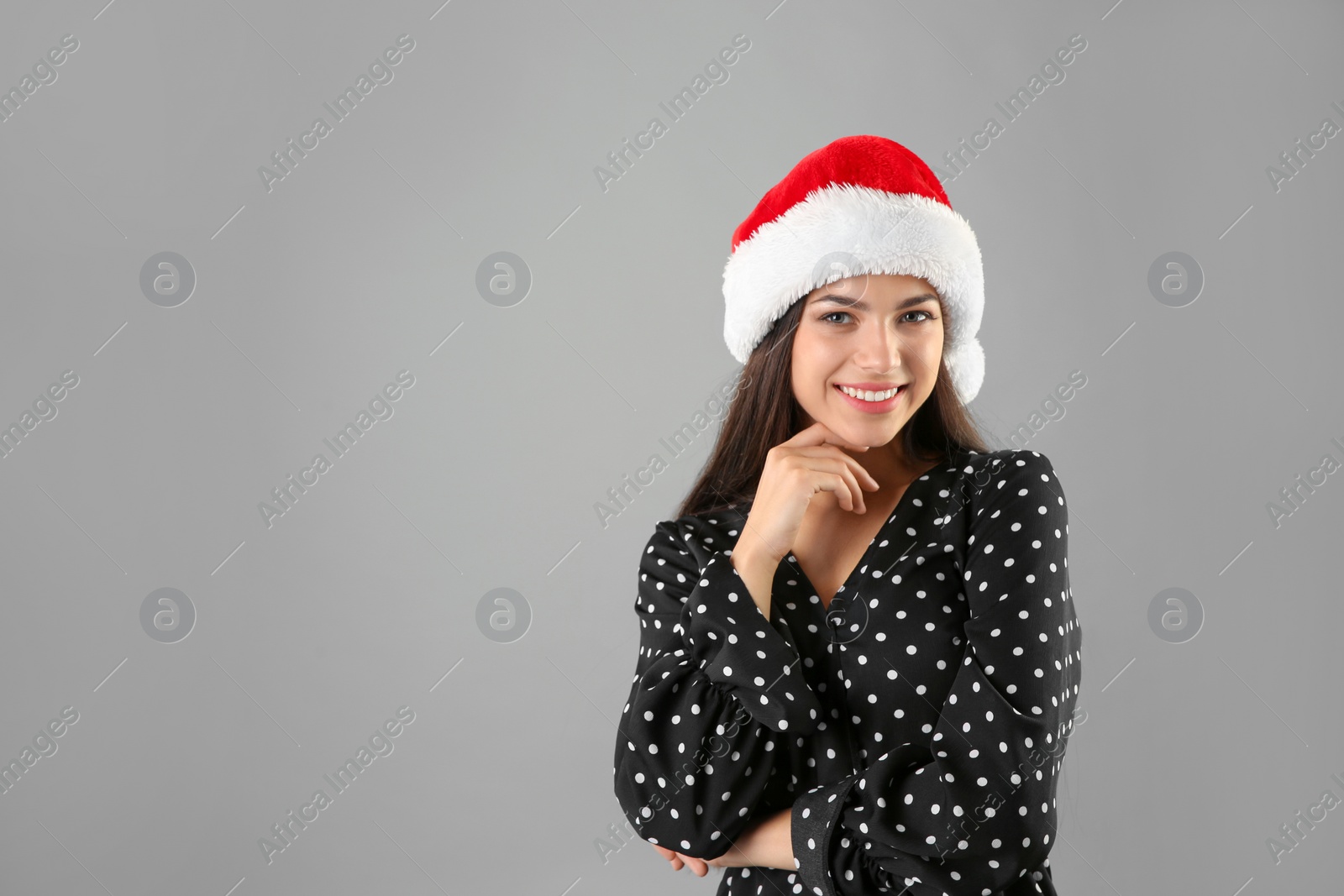 Photo of Young beautiful woman in Santa hat on grey background. Christmas celebration