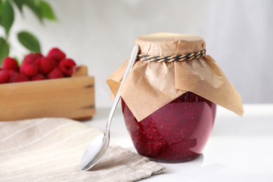 Delicious raspberry jam in jar on white table