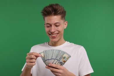 Photo of Happy man with dollar banknotes on green background