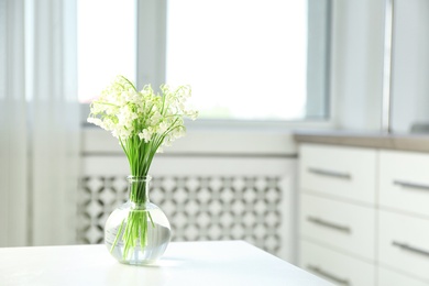 Photo of Vase with beautiful lily of the valley bouquet on table in room, space for text