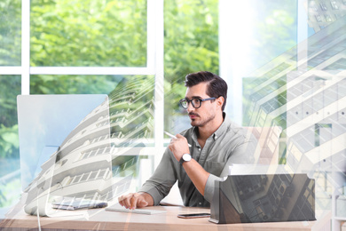 Image of Engineer working with computer at table in office and building. Double exposure