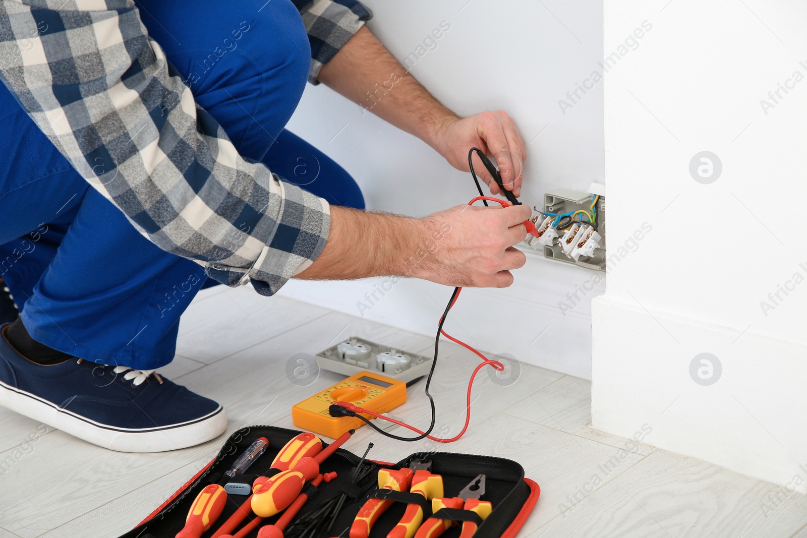 Photo of Electrician with tester checking voltage indoors, closeup