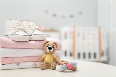 Stack of baby clothes, shoes and accessories on white table indoors, closeup