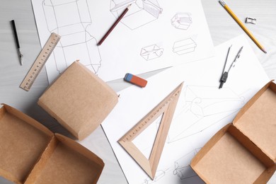 Creating packaging design. Drawings, boxes and stationery on light wooden table, flat lay