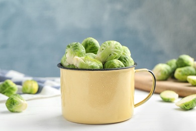 Metal mug with fresh Brussels sprouts on white table, closeup