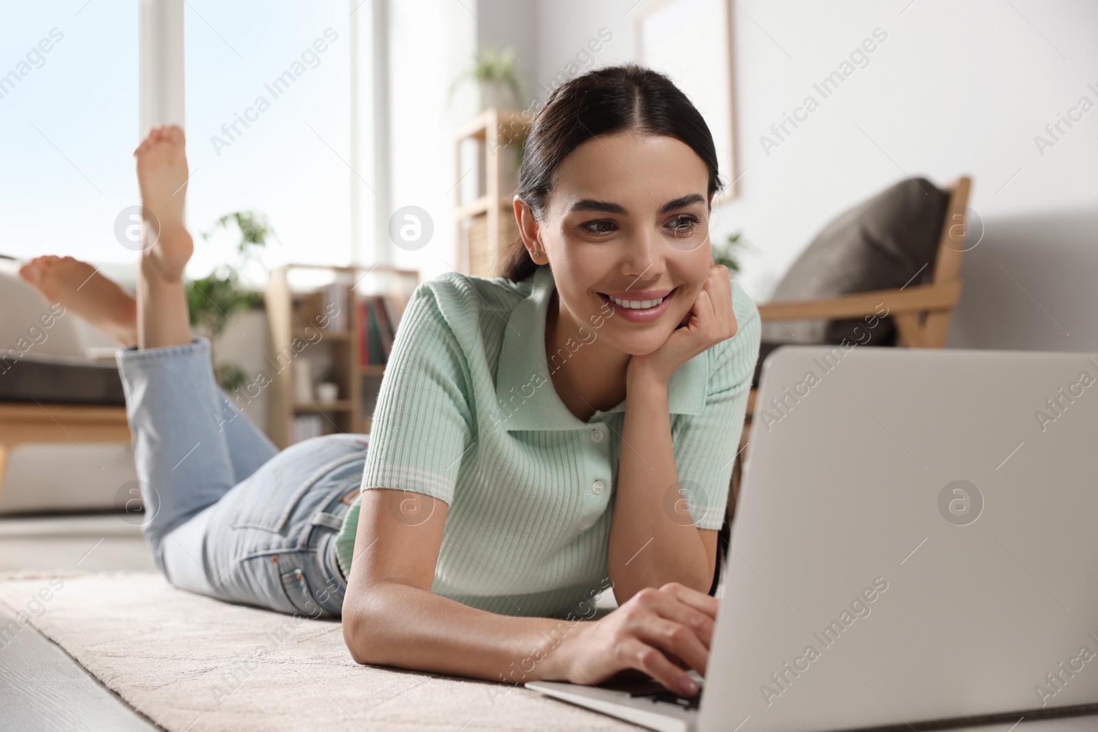 Photo of Young woman working with laptop on floor at home