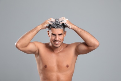 Photo of Handsome man washing hair on grey background