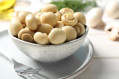 Photo of Delicious marinated mushrooms in bowl on white table, closeup