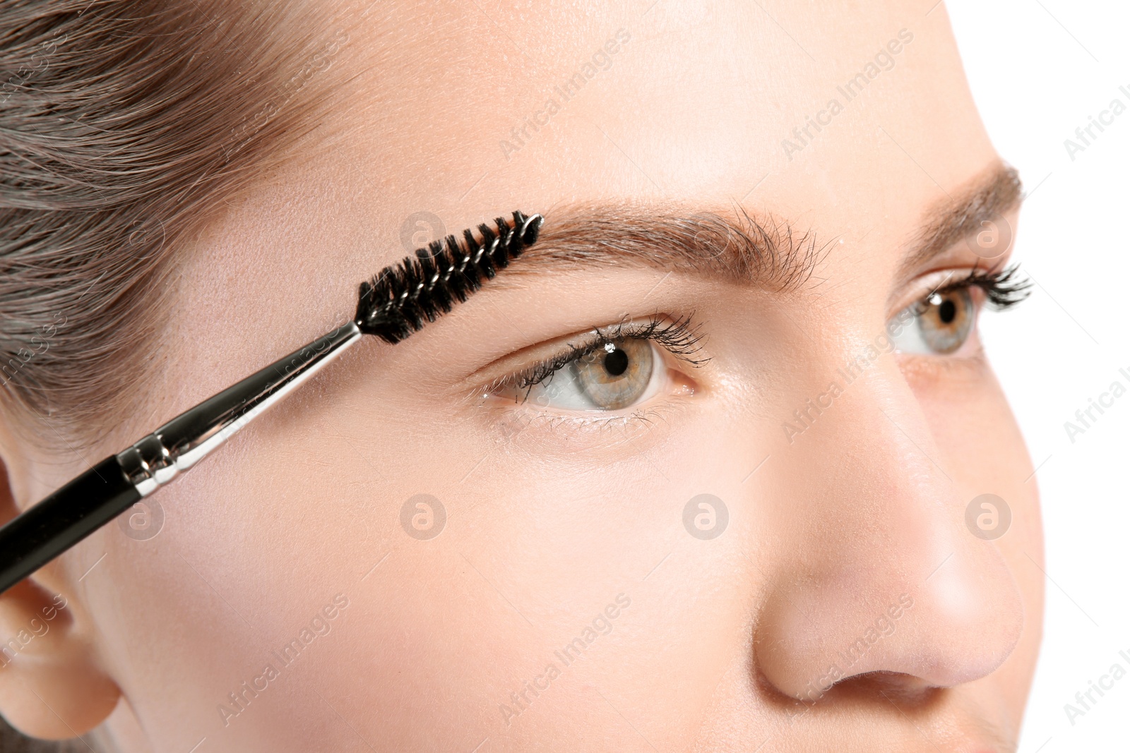 Photo of Beautiful woman with perfect eyebrows applying makeup on light background