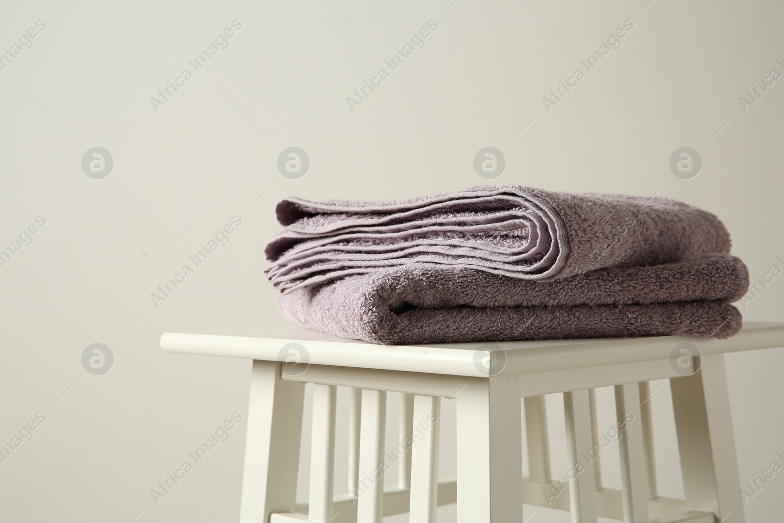 Photo of Violet towels on stool indoors. Space for text