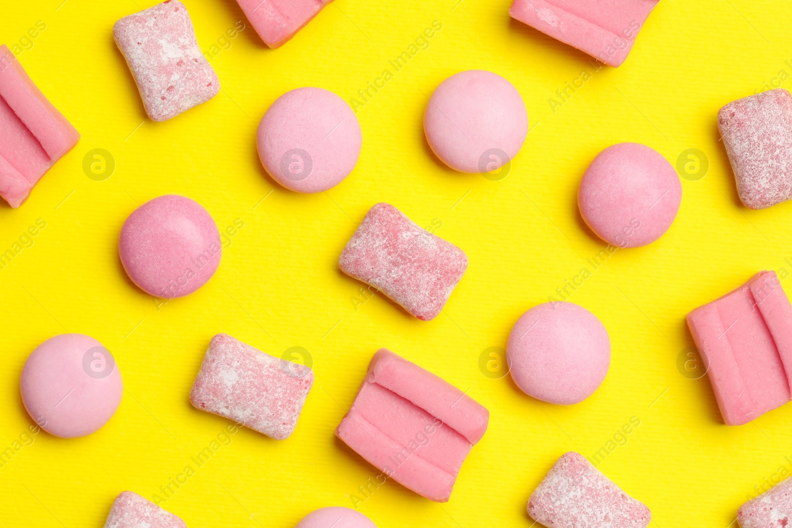 Photo of Pink bubble gums on yellow background, flat lay