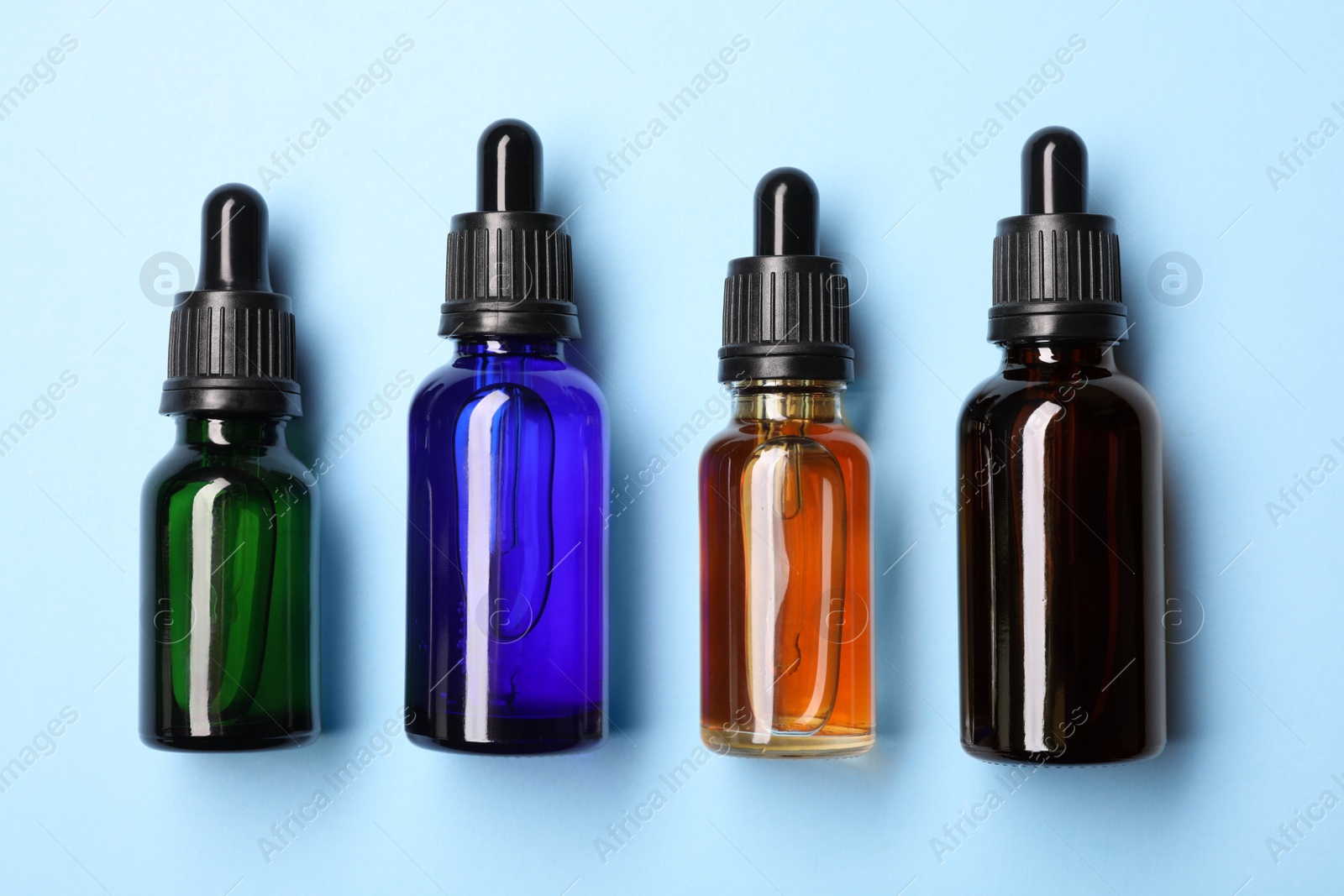 Photo of Flat lay composition with cosmetic bottles of essential oils on color background